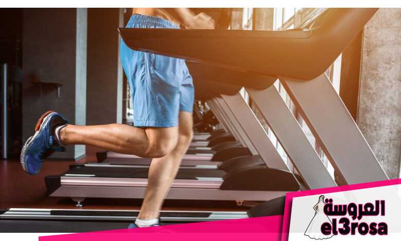 Person in blue shorts standing on treadmill kicking right leg back