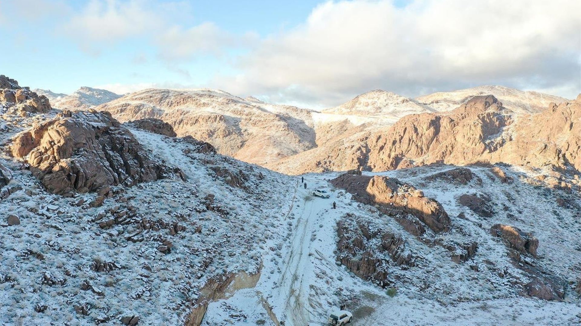 مدينة تبوك تعكس أشعة الشمس الخافتة على أرض مغطاة بالثلوج المتساقطة ببطء